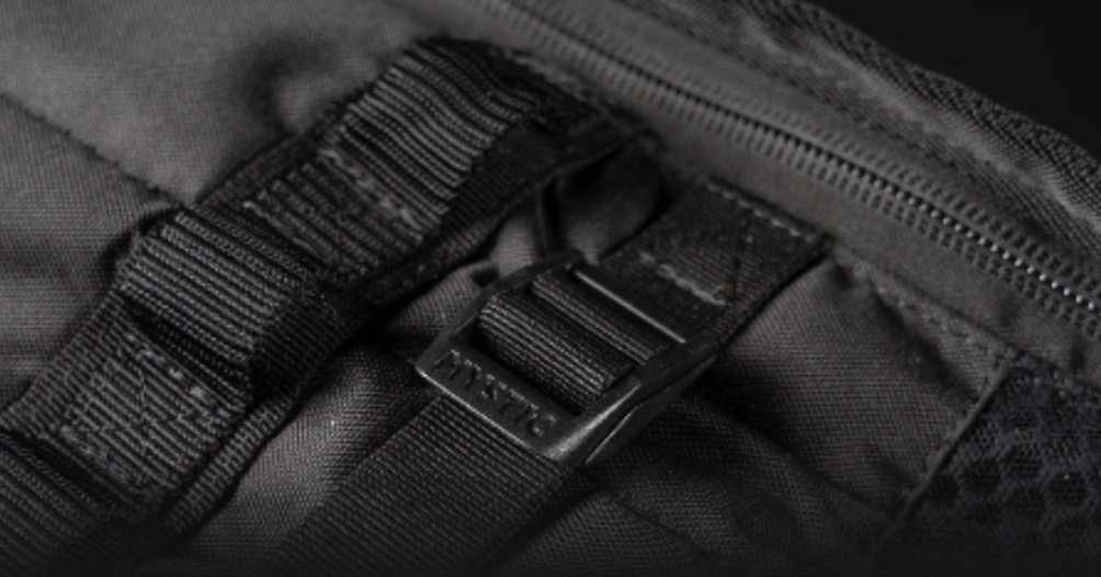 Close-up of a webbing strap and buckle beside the zip on a black board bag