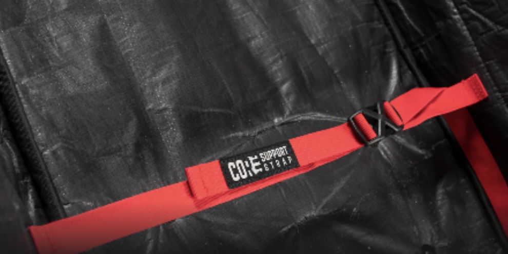 Red compression strap labelled Core Support Strap running across a black board bag