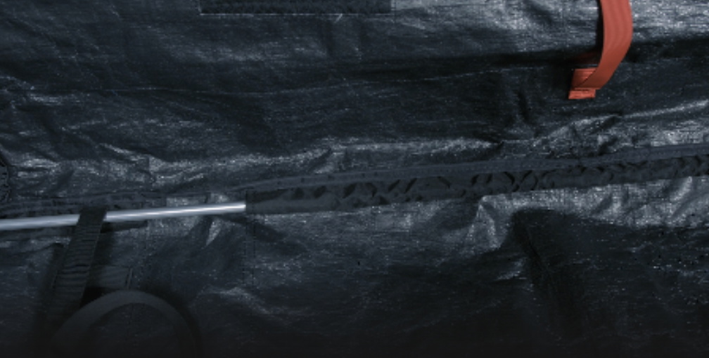 Close-up of the dark tarpaulin outer of a board bag with a red zip pull and cord