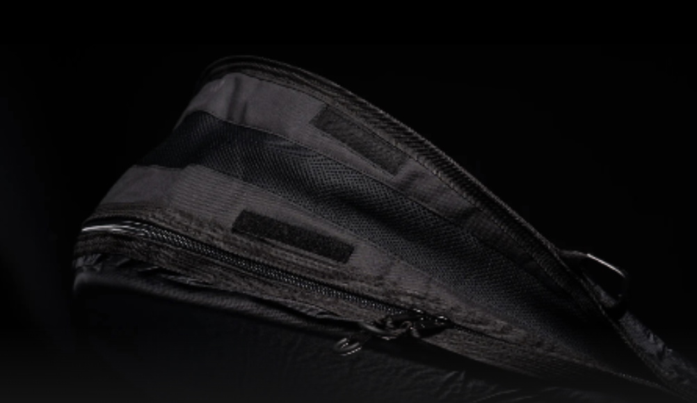 Tapered end of a black board bag with its full-length zip, shot on a dark background