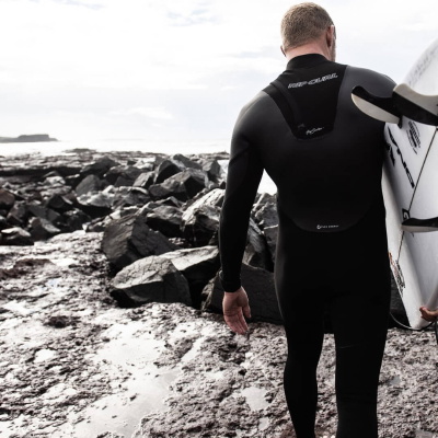 Surfeur en combinaison enfilant un gant au bord de la mer