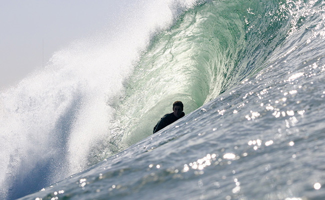 Surfer putting on a chest-zip wetsuit
