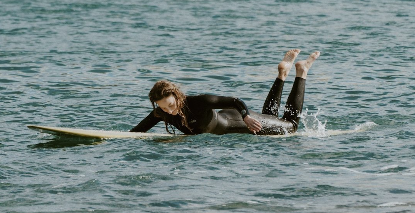 Deux surfeurs en combinaison noire ramant ensemble sur un même longboard