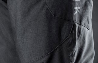 Close-up of a shaped pocket seam and embossed logo on dark grey technical trousers