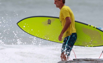 Homme courant vers la mer avec une planche de surf